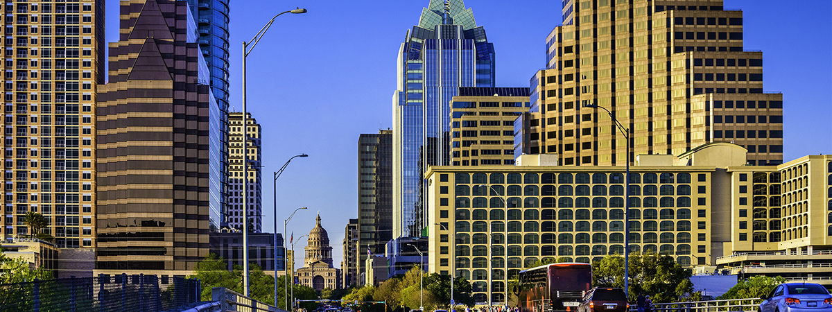 Downtown Austin skyscrapers surrounding Texas Capitol with busy cars, people